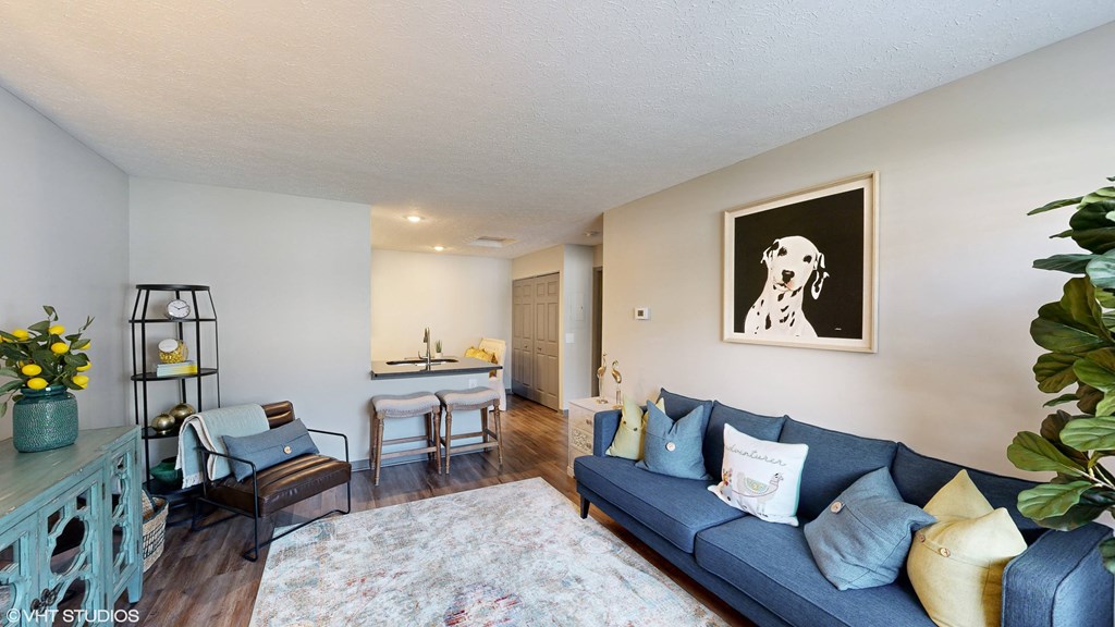 a living room with a blue couch and a kitchen with a table and chairs at Springburne at Polaris Apartments, Columbus