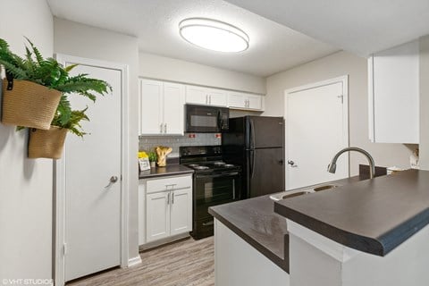 a kitchen with black appliances and white cabinets and a counter top a kitchen with black appliances and white cabinets and a counter top at The Local Apartments, Memphis, 38115