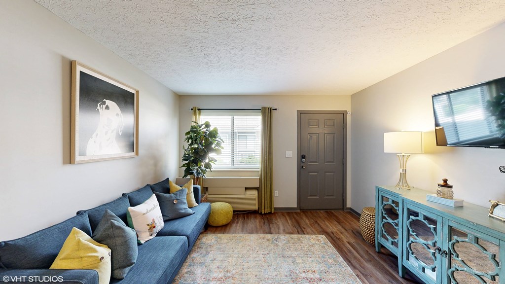 a living room with a blue couch and a door to a hallway at Springburne at Polaris Apartments, Ohio, 43235