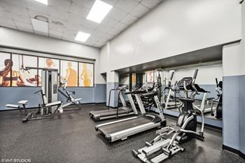 a gym with treadmills and other exercise equipment in a building with windows at Delmar Loop Apartments, St. Louis, MO, 63112