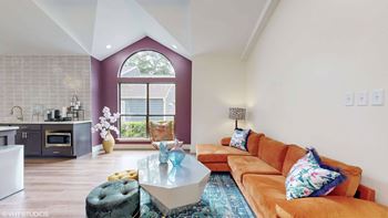 A modern living room with a large window and a kitchen area.