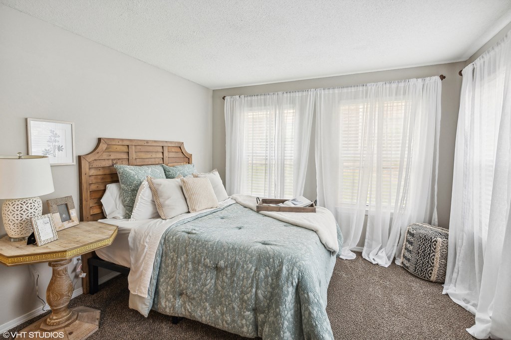 a bedroom with a bed and windows with white curtains at The Local Apartments, Tennessee, 38115