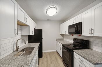 a kitchen with granite counter tops and white cabinets