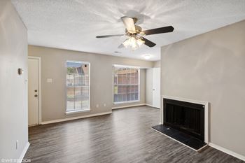 an empty living room with a fireplace and a ceiling fan at The Birches Apartment Homes, Memphis