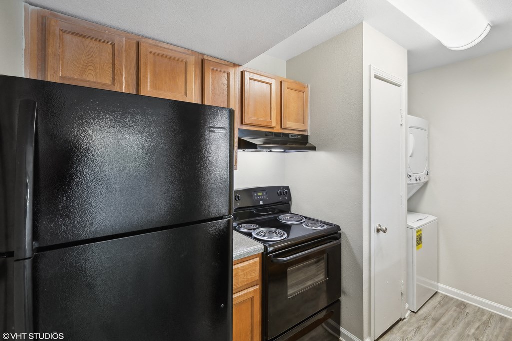 a kitchen with black appliances and wood cabinets at The Nova Apartments, Memphis, TN