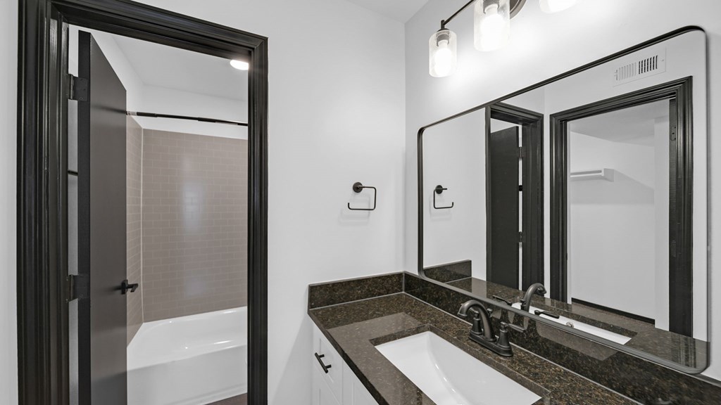 A modern bathroom with a marble countertop and a large mirror. at The District Apartments, Memphis, 38115