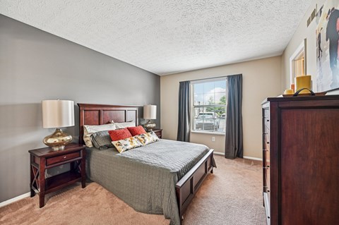 A bedroom with a large bed and a window overlooking a balcony.