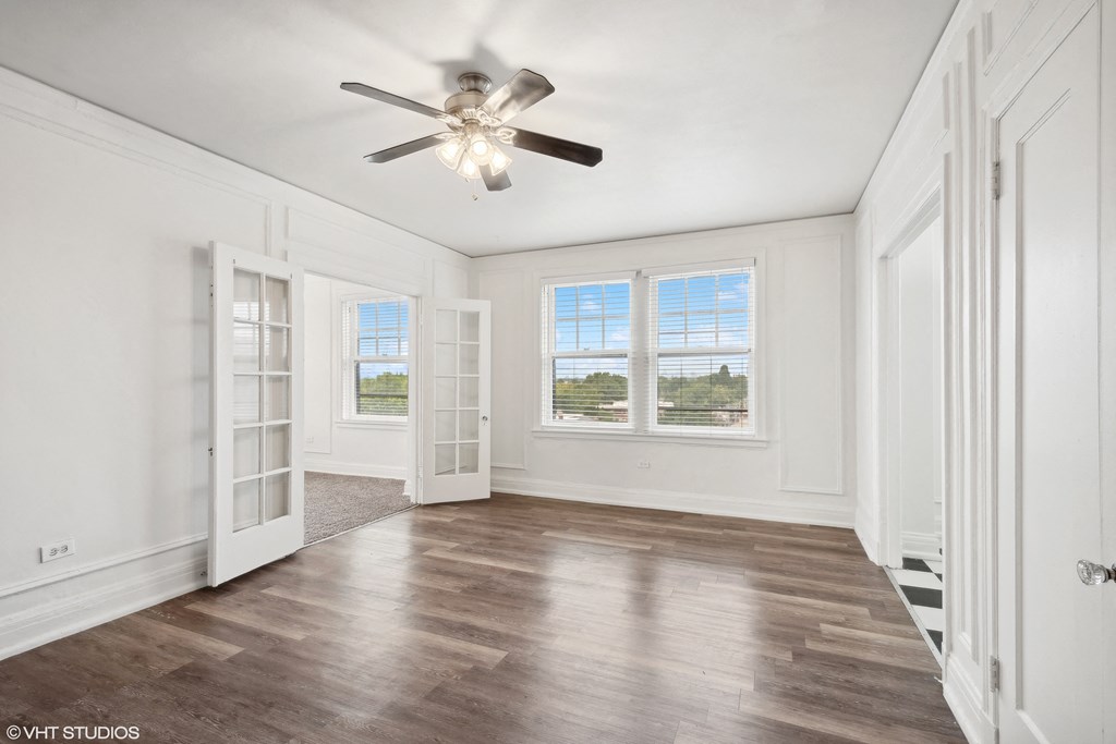 an empty living room with white walls and a ceiling fan  at The Embassy in St Louis