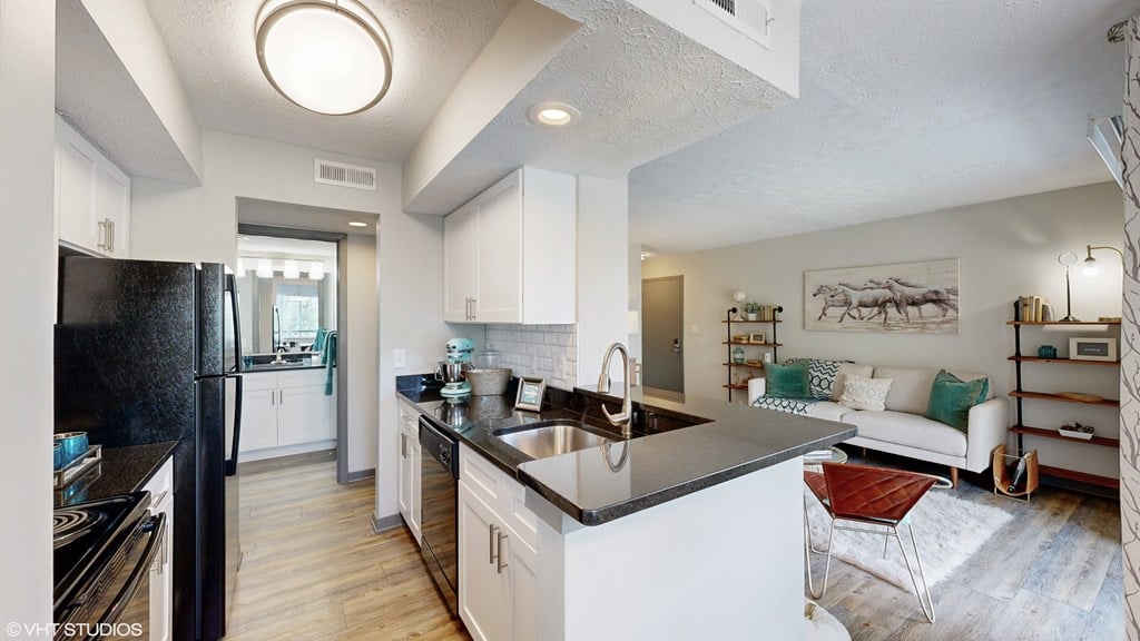an open kitchen and living room with a black counter top an open kitchen and living room with a black counter top at Runaway Bay Apartments, Columbus, 43204