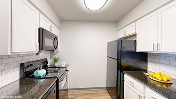 a kitchen with black appliances and white cabinets at Springburne at Polaris Apartments, Columbus, Ohio