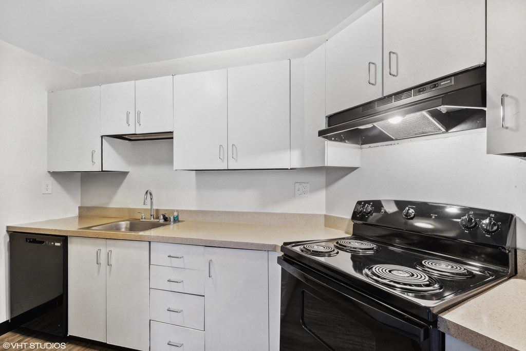 a kitchen with white cabinets and black appliances and a sink a kitchen with white cabinets and black appliances and a sink at Delmar Loop Apartments, Missouri