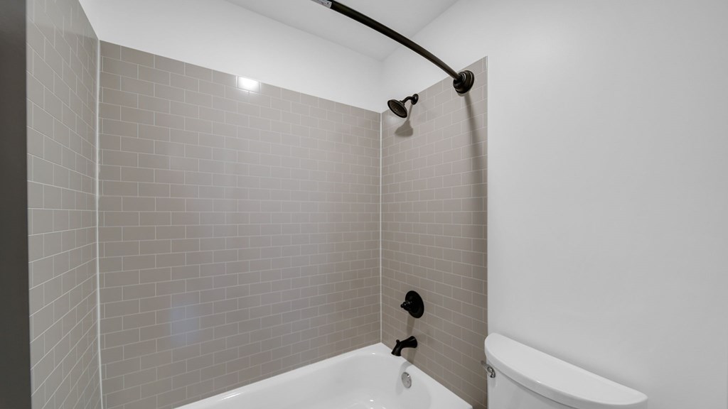 A white bathtub with a shower head and hand held shower. at The District Apartments, Memphis, Tennessee