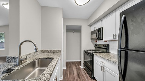A kitchen with a sink, stove, and refrigerator.