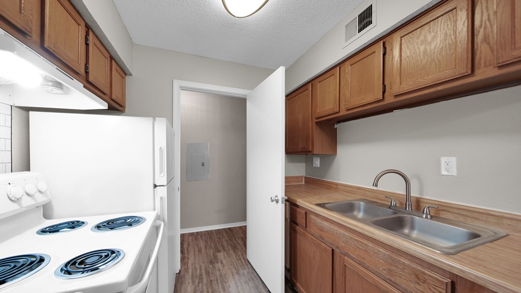 A kitchen with a white stove top oven and wooden cabinets. at The Local Apartments, Memphis