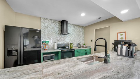 A kitchen with a marble countertop and green cabinets.