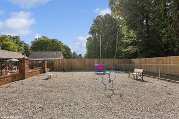 a fenced in backyard with a playground and swings and a bench at The Birches Apartment Homes, Tennessee, 38133