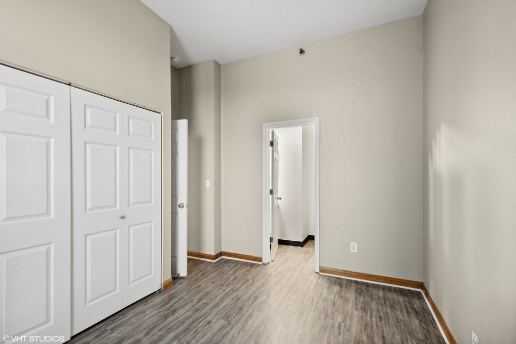 an empty bedroom with white doors and wood flooring an empty bedroom with white doors and wood flooring at Delmar Loop Apartments, Missouri, 63112
