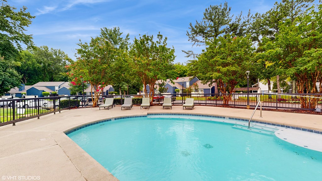 our resort style swimming pool is next to our yard with chairs and trees at The Vale Apartments and Townhomes, Cordova, TN