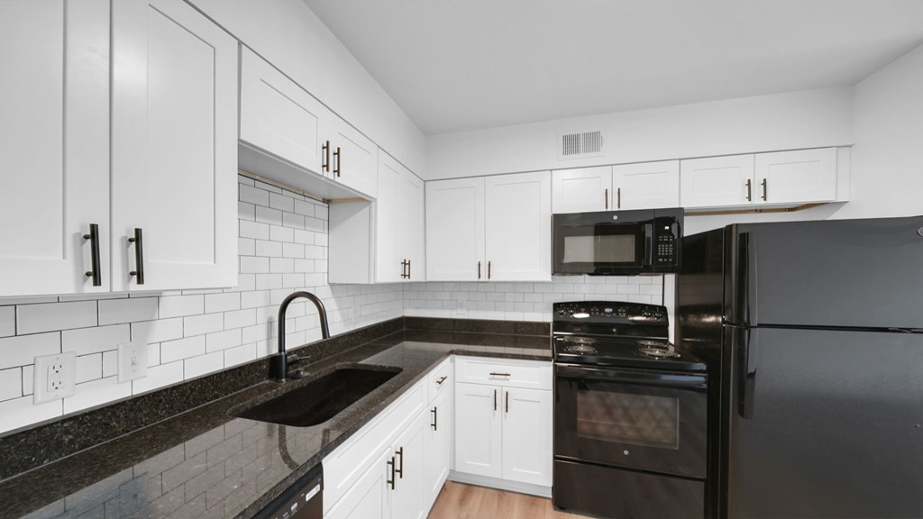 A kitchen with black appliances and white cabinets. at The District Apartments, Tennessee