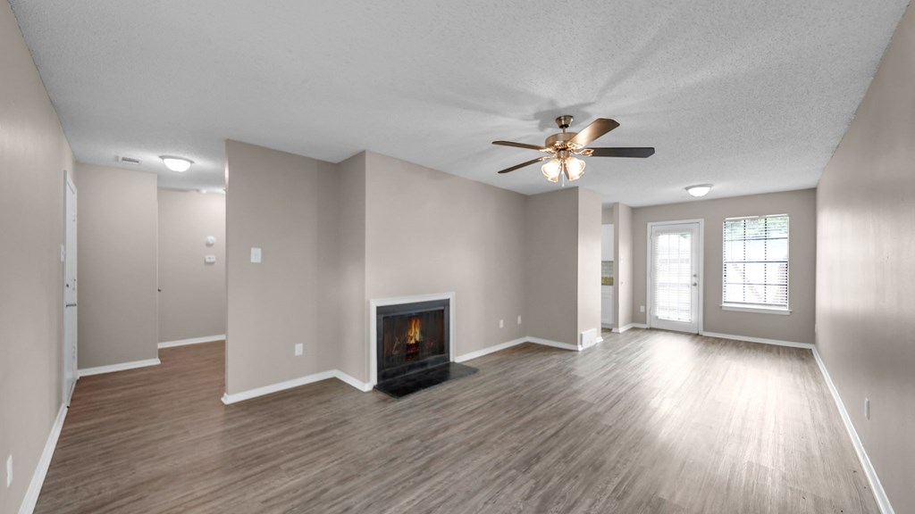 A spacious room with a fireplace and a ceiling fan.