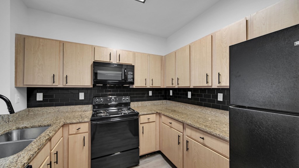 A kitchen with black appliances and wooden cabinets.