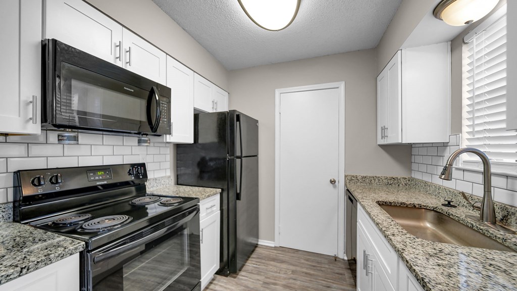 A kitchen with black appliances and white cabinets.