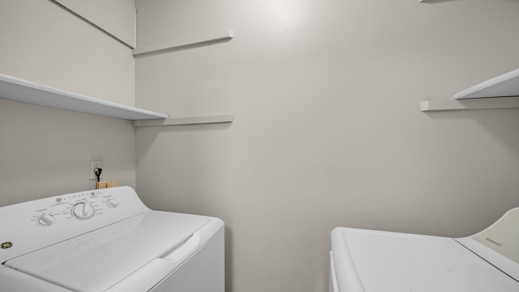 Two white washing machines in a small laundry room.