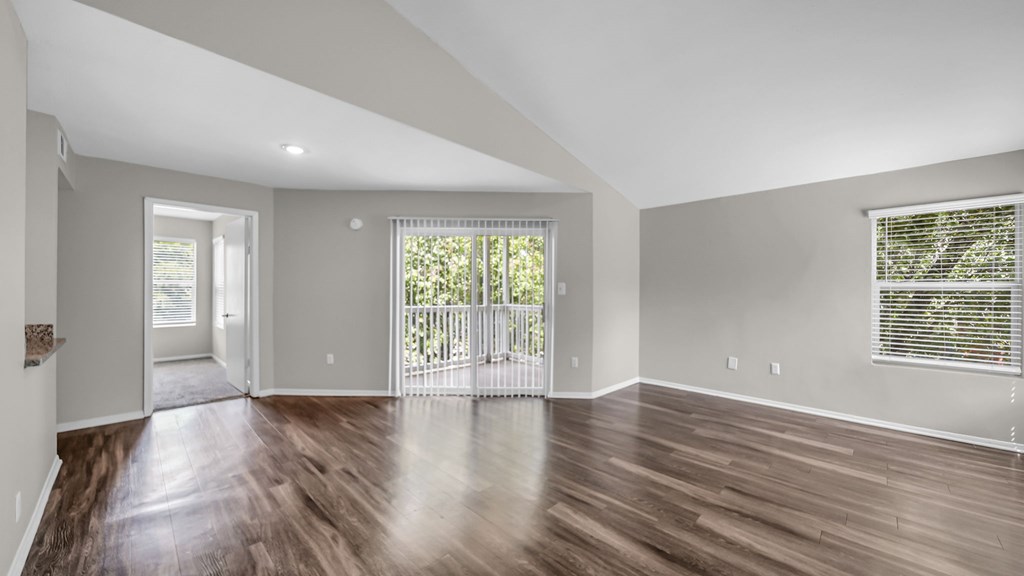 A spacious room with wooden floors and a large window.