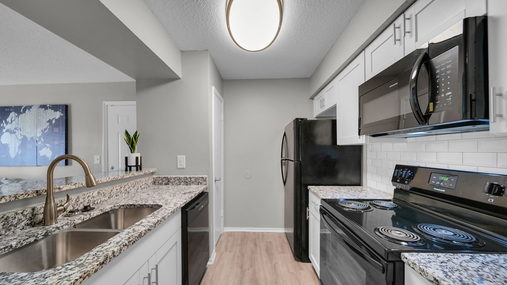 A kitchen with a black fridge, black microwave, and black oven. at The District Apartments, Memphis, TN