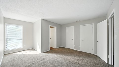 A sparsely furnished room with a carpeted floor and white walls.