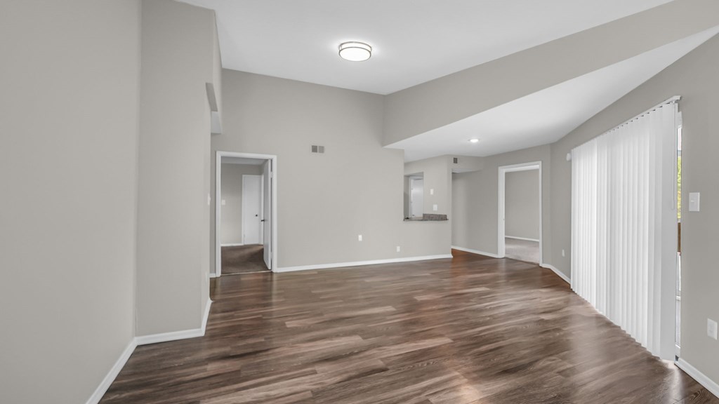 A spacious room with wooden flooring and white walls.