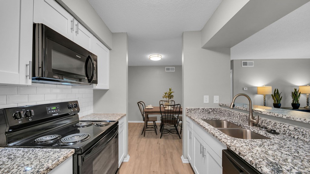 A kitchen with granite countertops and a black stove top oven. at The District Apartments, Memphis, 38115
