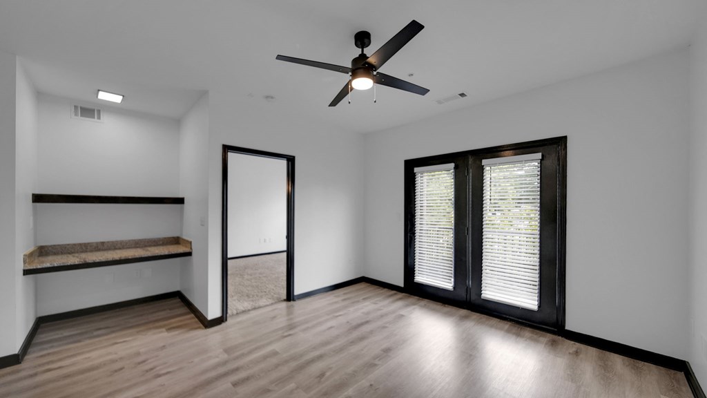A room with a ceiling fan and a window with blinds.