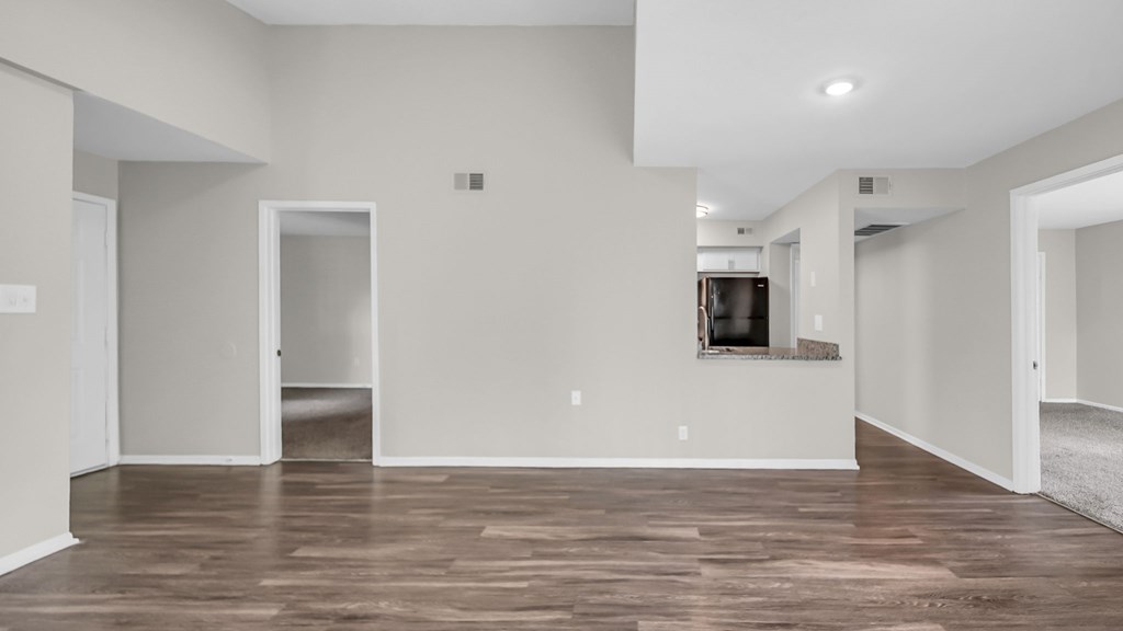 A spacious living room with wood flooring and white walls.