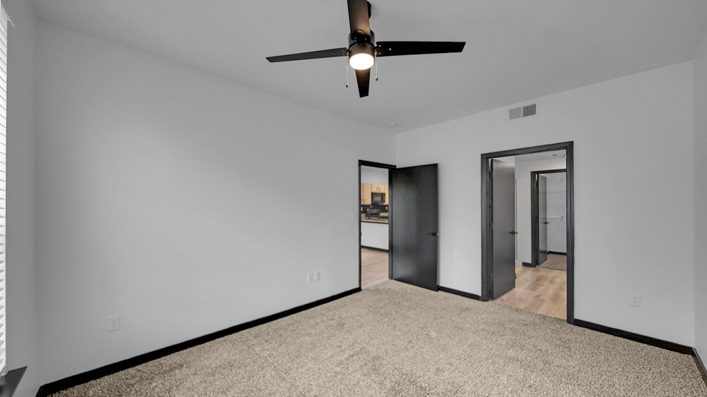 A room with a ceiling fan and carpeted floor.