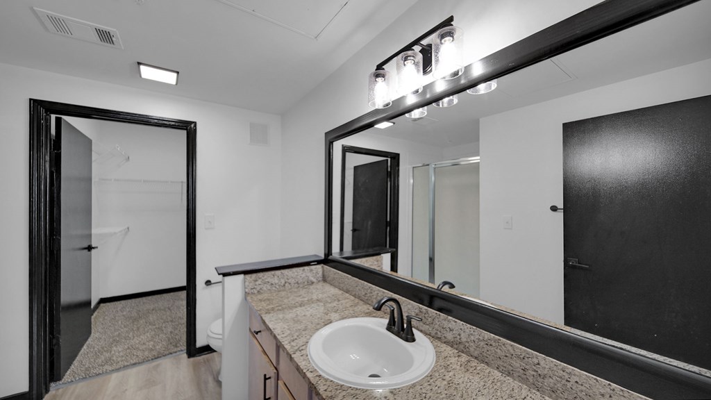 A bathroom with a sink, mirror, and lighting fixture.