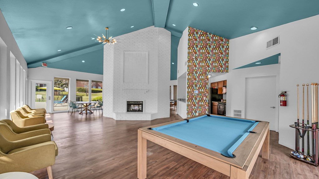 A pool table is in the middle of a room with a fireplace and a chair.
