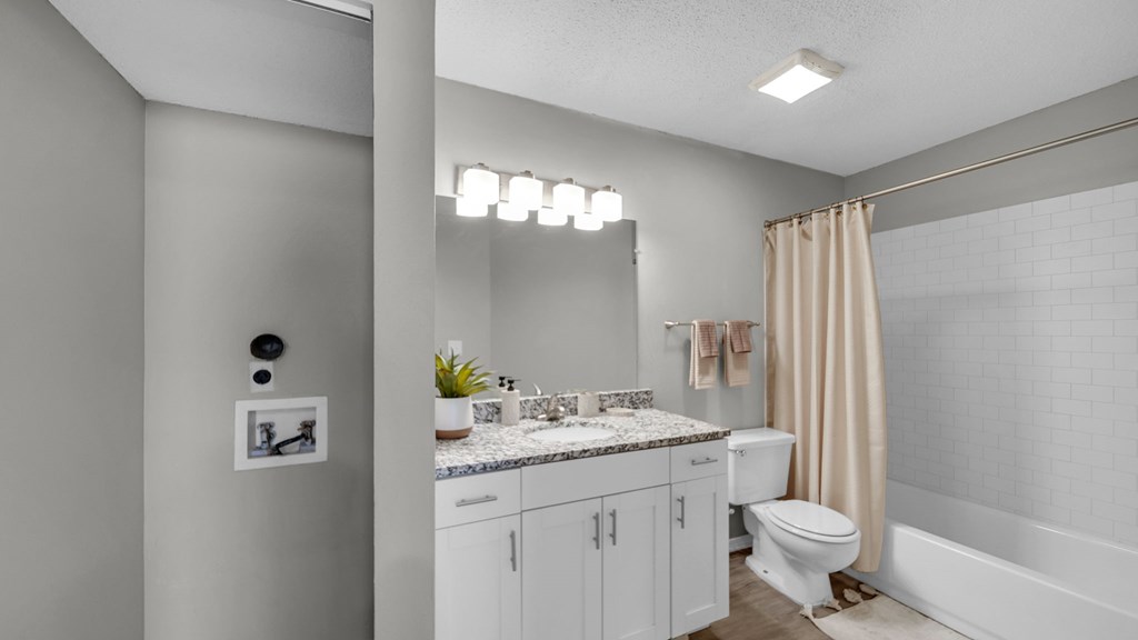 A bathroom with a toilet, sink, and shower. at The District Apartments, Memphis, Tennessee