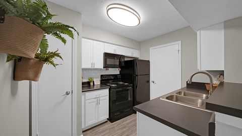 A kitchen with a black refrigerator and white cabinets.