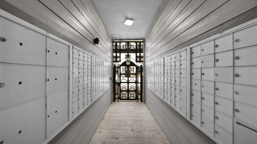 A long hallway with white lockers on both sides and a door at the end.