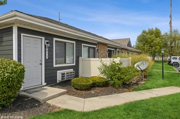 the front of a gray house with a white door and a driveway