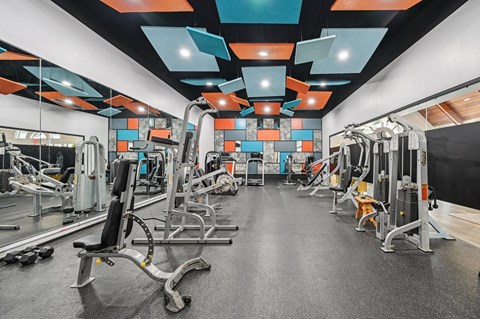 A gym with a variety of equipment including weights and machines.