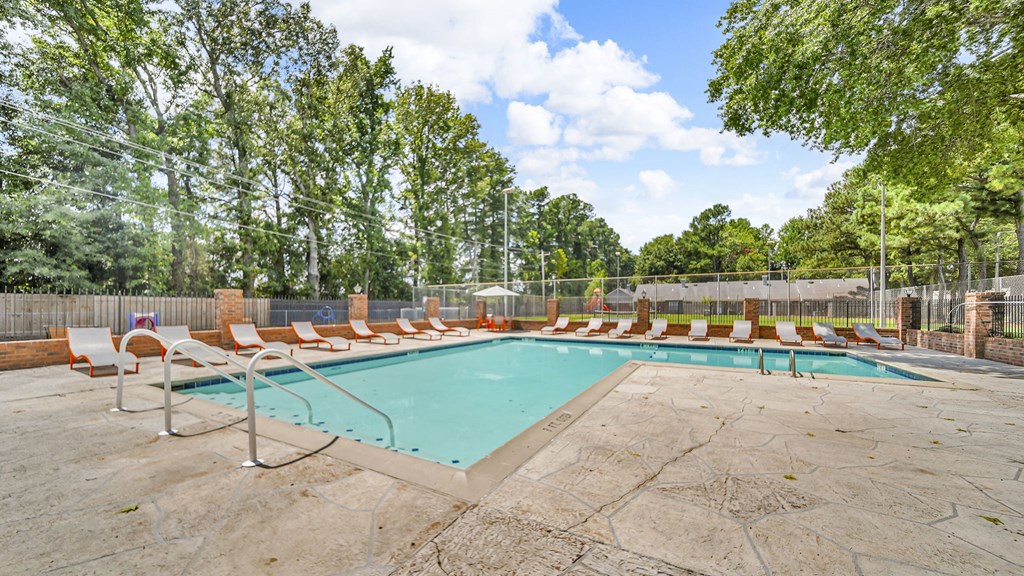 A large outdoor swimming pool surrounded by trees and lounge chairs.