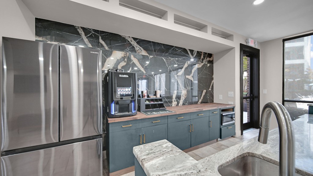 A modern kitchen with a stainless steel refrigerator and a marble countertop.