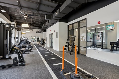 A gym with a variety of equipment including treadmills, weights, and exercise machines.