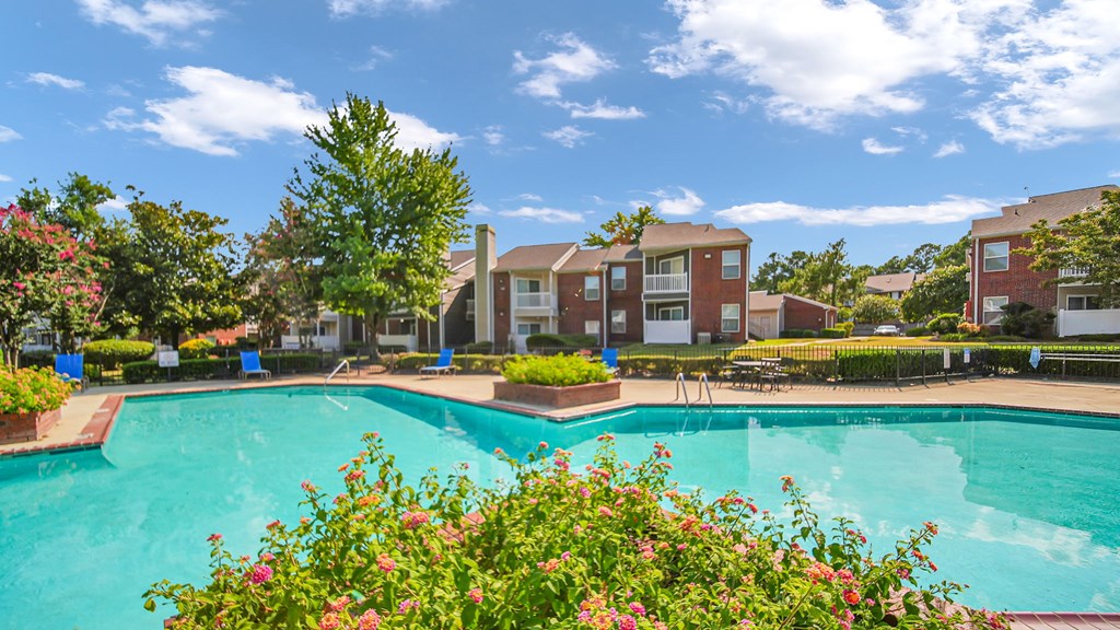 A swimming pool surrounded by flowers and residential buildings.