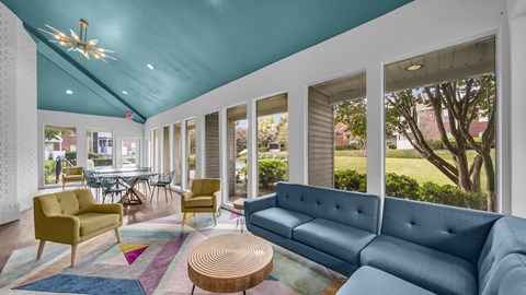 A brightly lit living room with a blue couch and yellow chairs.