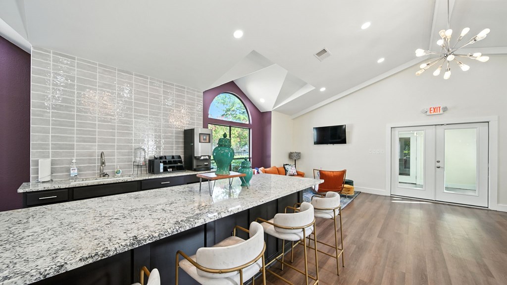 A kitchen with a marble countertop and a purple backsplash.