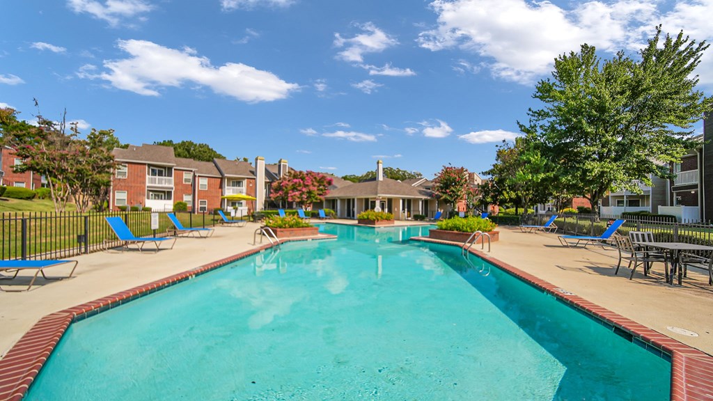 A large swimming pool surrounded by lounge chairs and trees.