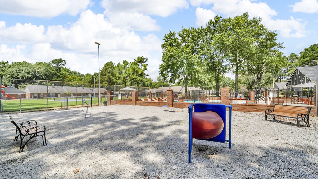 A playground with a blue and red ball, a swing set, and a bench.